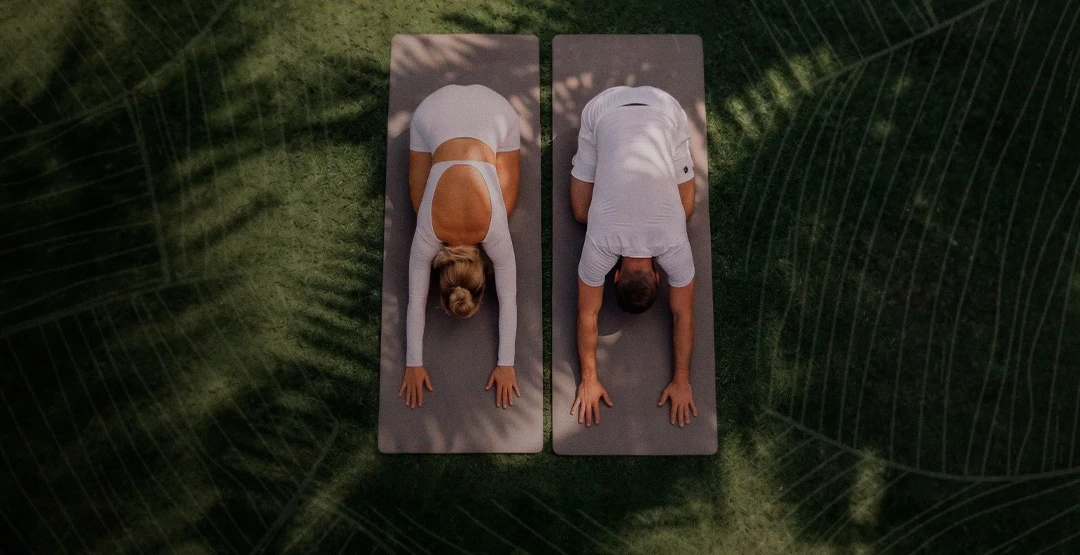 Casal praticando yoga sobre a grama no Pátio Wellness — Edição Pátio Run